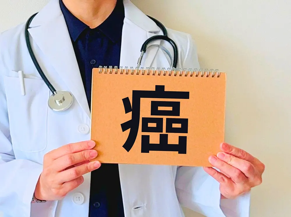 「癌」と書かれたカードを持つ白衣の医師