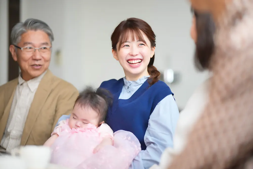 赤ちゃんを抱く家族と笑顔の女性スタッフ（家族の健康サポート）